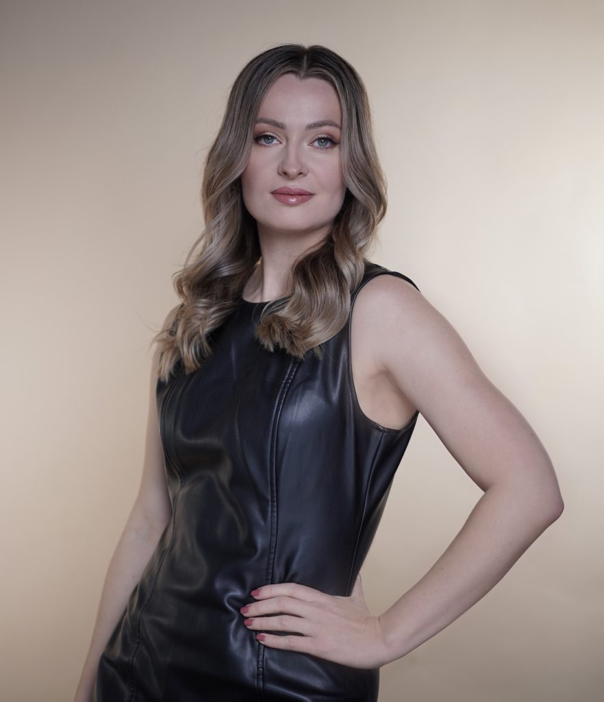Close-up-of-woman-with-long-hair-in-black-leather-dress-against-neutral-background