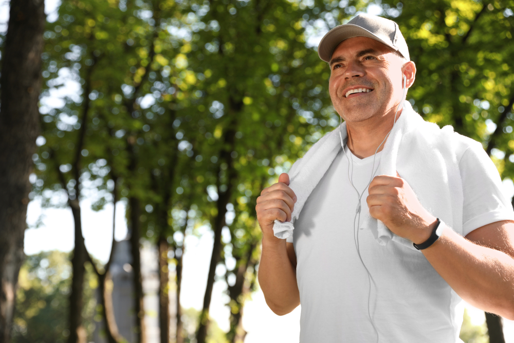 Smiling middle-aged man with towel over shoulders enjoying a walk.