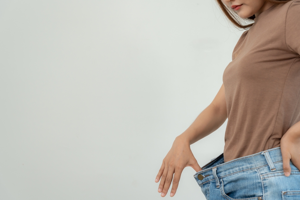 Close-up-of-woman-holding-loose-jeans-showing-weight-loss-success